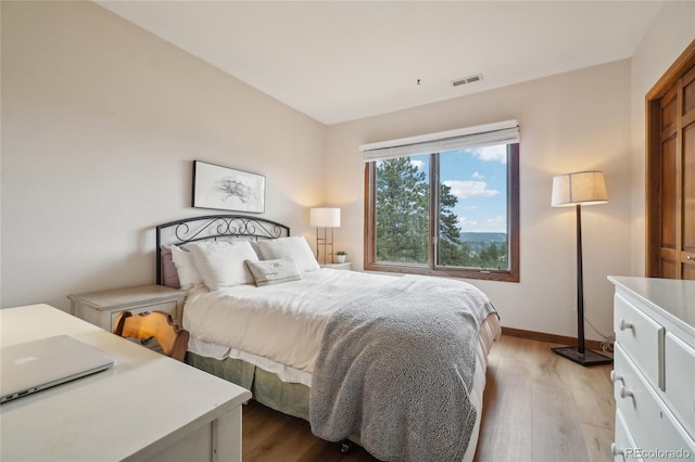 bedroom featuring baseboards, light wood finished floors, and visible vents