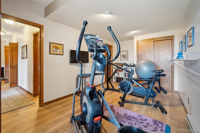 workout area with baseboards and wood finished floors