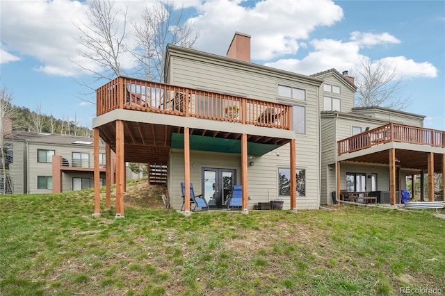 rear view of property featuring a lawn, a deck, and a chimney