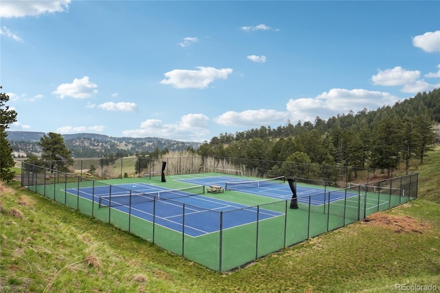 view of tennis court with fence and a mountain view
