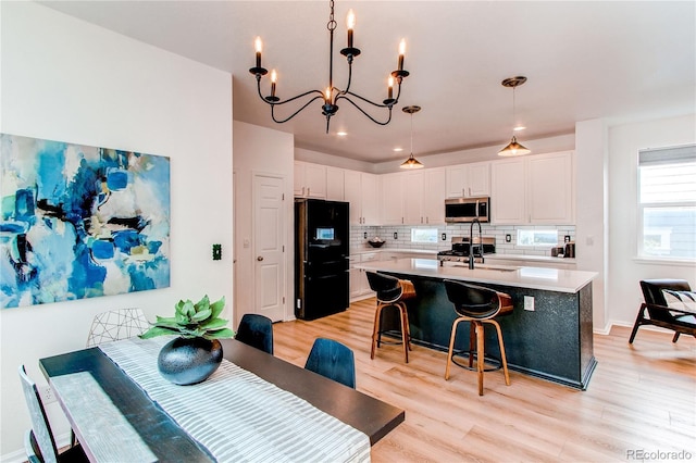 kitchen featuring freestanding refrigerator, white cabinetry, stainless steel microwave, and light wood finished floors