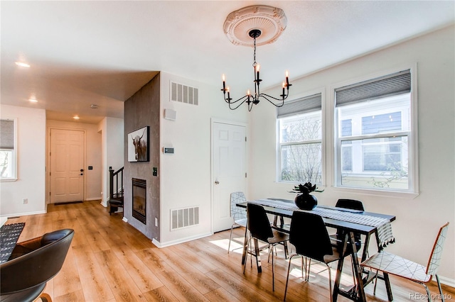 dining space with an inviting chandelier, baseboards, light wood-style floors, and visible vents