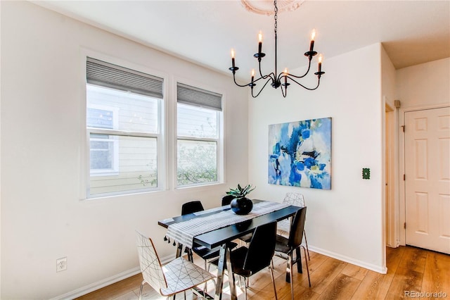 dining area featuring baseboards, light wood-style flooring, and a chandelier
