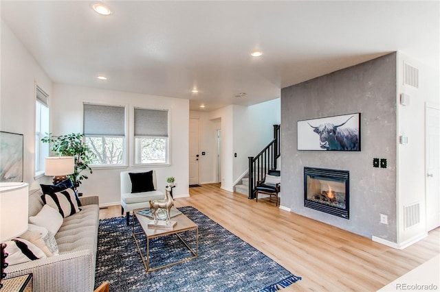 living area featuring visible vents, stairs, wood finished floors, recessed lighting, and a large fireplace