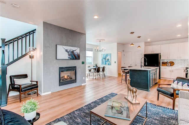living room with light wood-style floors, recessed lighting, baseboards, and a notable chandelier