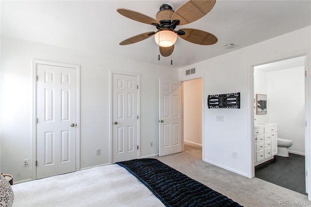 carpeted bedroom with a ceiling fan, visible vents, baseboards, multiple closets, and ensuite bath