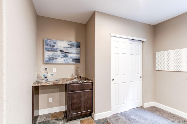 bar featuring baseboards, wet bar, and a sink