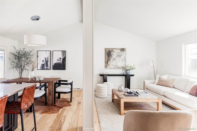 living area featuring visible vents, vaulted ceiling with beams, and light wood finished floors