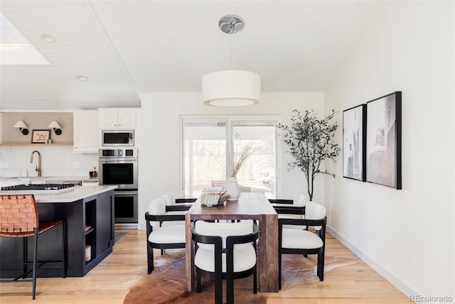 dining space featuring light wood-style flooring and baseboards