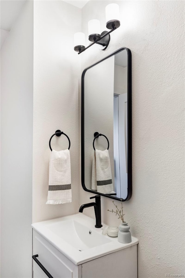 bathroom with a textured wall and vanity