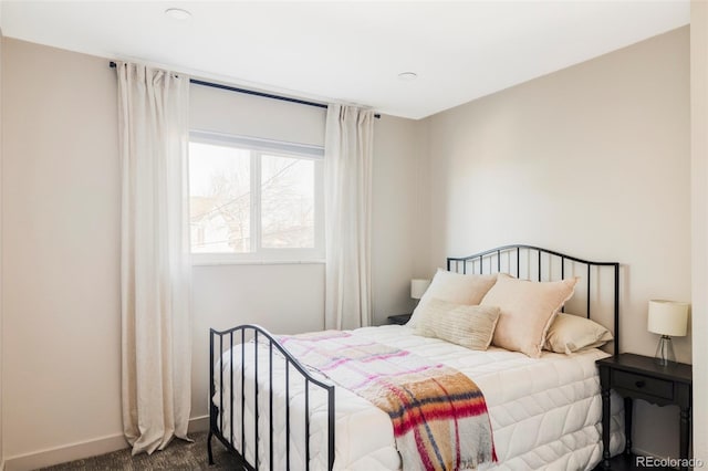 bedroom featuring dark carpet and baseboards