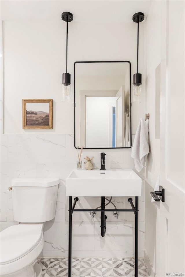 half bath featuring a sink, tile walls, and toilet