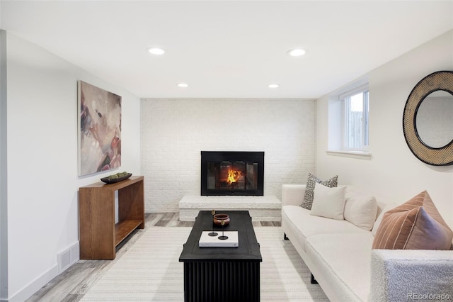 living room with recessed lighting, a fireplace, visible vents, baseboards, and light wood finished floors