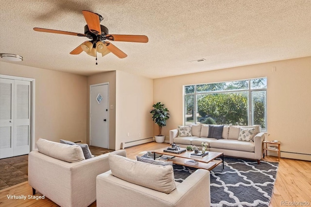 living room with visible vents, a ceiling fan, a textured ceiling, baseboard heating, and wood finished floors