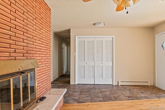 interior space with a textured ceiling, a closet, stone finish floor, a ceiling fan, and baseboard heating