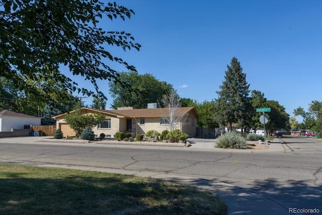 ranch-style house with a chimney and fence
