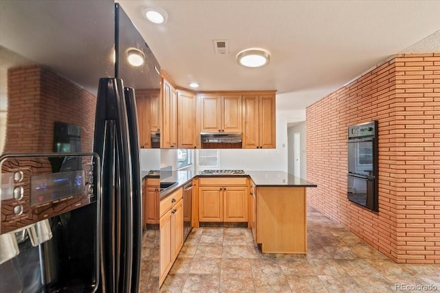 kitchen featuring a peninsula, light brown cabinetry, black appliances, under cabinet range hood, and brick wall