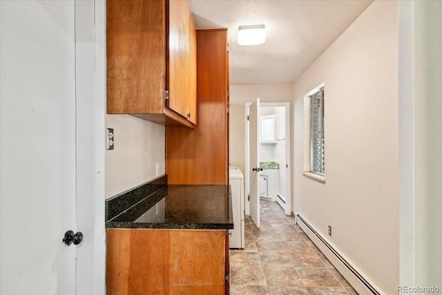 kitchen featuring washer / dryer, brown cabinets, baseboard heating, and dark stone counters