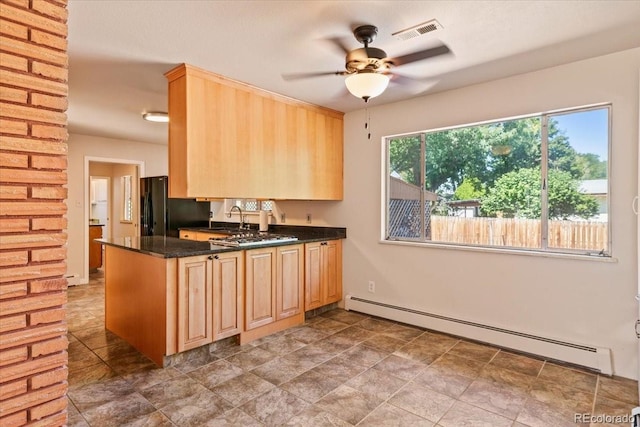 kitchen featuring visible vents, a baseboard radiator, freestanding refrigerator, and light brown cabinetry