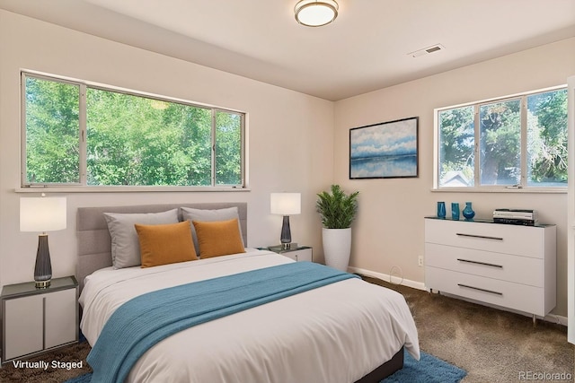 bedroom with visible vents, dark colored carpet, multiple windows, and baseboards