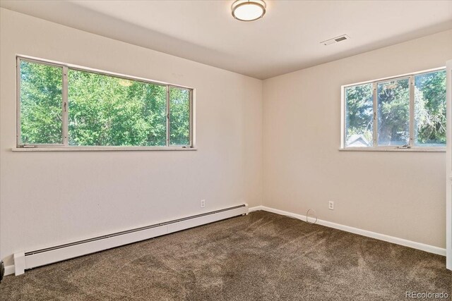 empty room featuring baseboard heating, baseboards, dark carpet, and visible vents