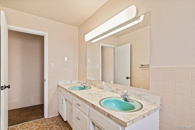 bathroom featuring double vanity, a sink, wainscoting, and tile walls