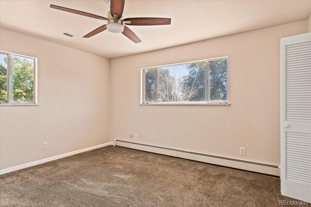 unfurnished bedroom with a baseboard heating unit, baseboards, visible vents, ceiling fan, and carpet