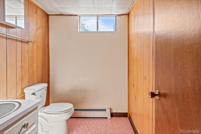 bathroom with baseboards, toilet, a baseboard radiator, vanity, and wood walls