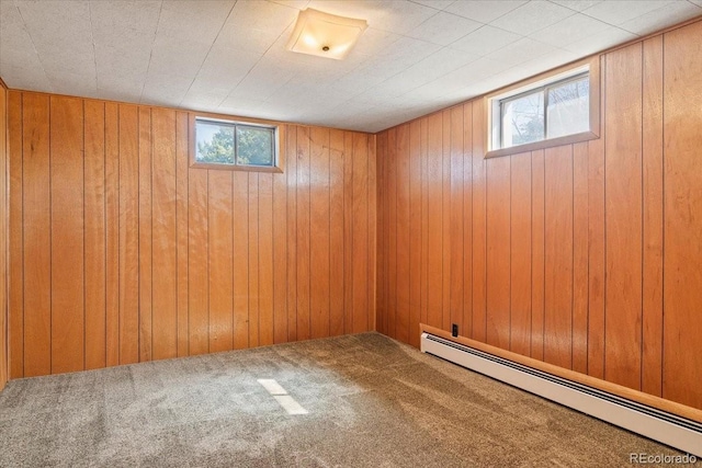basement with wood walls, a baseboard heating unit, and carpet floors