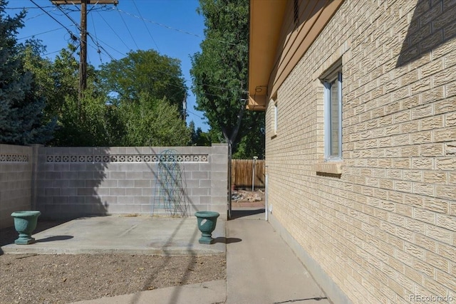 view of side of home with a fenced backyard, a patio area, and brick siding