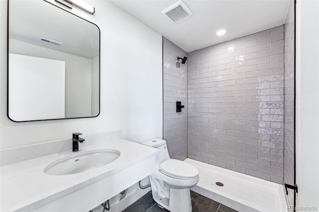 bathroom featuring tile patterned floors, toilet, sink, and a tile shower