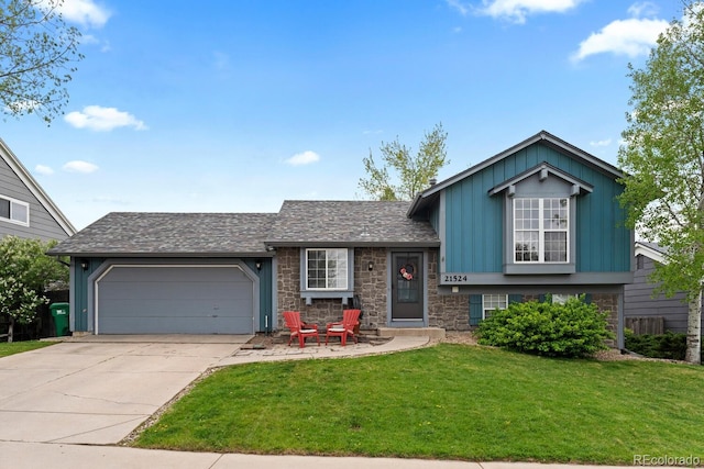 split level home with stone siding, driveway, a garage, a front yard, and board and batten siding