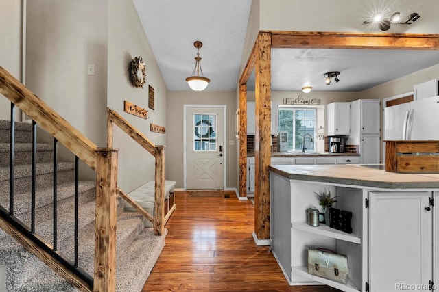 interior space with open shelves, white cabinetry, wood finished floors, and a sink