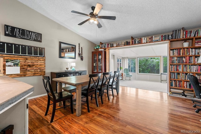 dining area with a textured ceiling, vaulted ceiling, wood finished floors, and ceiling fan