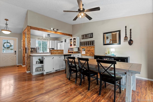 dining space with a ceiling fan, dark wood-style flooring, baseboards, and a textured ceiling