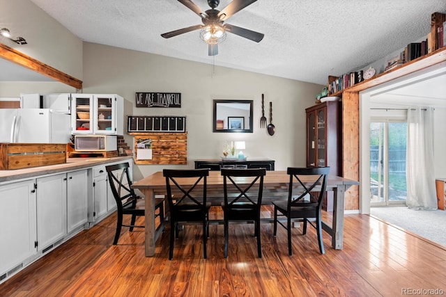 dining room featuring lofted ceiling, a textured ceiling, a ceiling fan, and dark wood finished floors