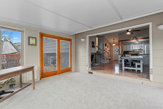 unfurnished living room with a ceiling fan, stairway, visible vents, and carpet floors