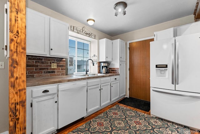 kitchen featuring a sink, white appliances, white cabinetry, and dark countertops