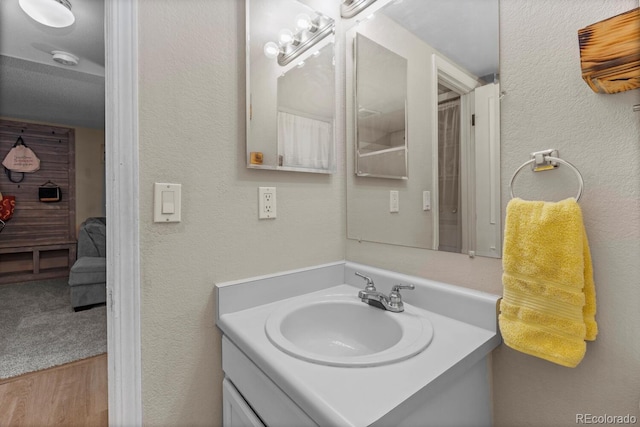 ensuite bathroom with vanity, a textured wall, and ensuite bath