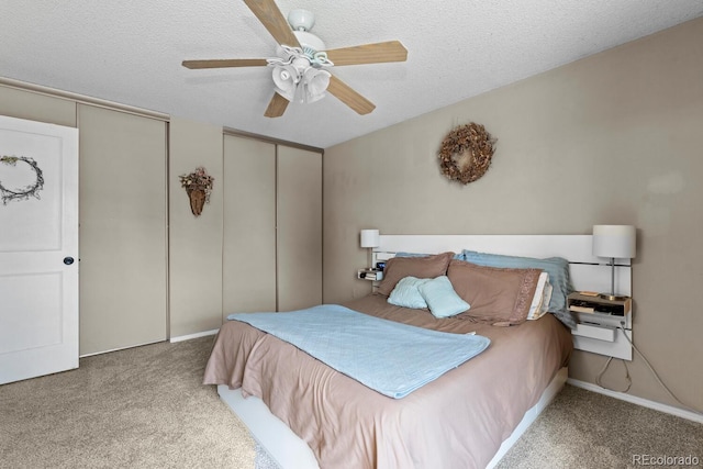 carpeted bedroom with multiple closets, ceiling fan, and a textured ceiling