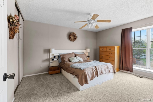 carpeted bedroom featuring a textured ceiling, visible vents, and ceiling fan