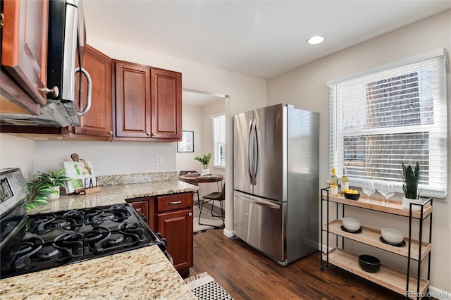 kitchen featuring appliances with stainless steel finishes, dark hardwood / wood-style floors, and light stone counters