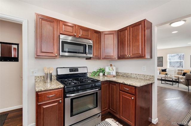 kitchen with light stone counters, stainless steel appliances, and dark hardwood / wood-style floors