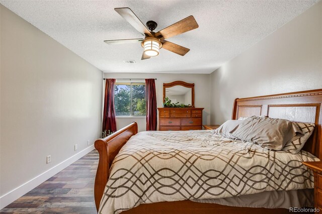 bedroom featuring dark hardwood / wood-style flooring, ceiling fan, and a textured ceiling