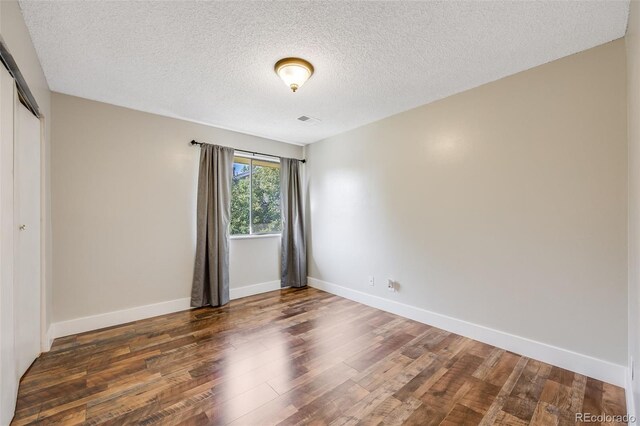 unfurnished room featuring dark wood-type flooring and a textured ceiling