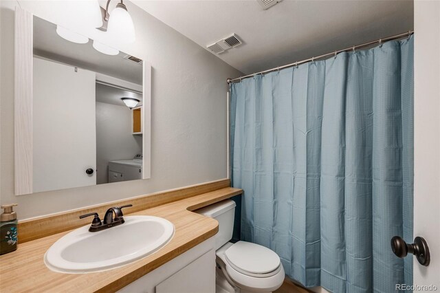 bathroom with vanity, toilet, washer / dryer, and a shower with shower curtain