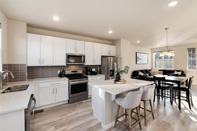 kitchen featuring backsplash, a kitchen island, a breakfast bar area, appliances with stainless steel finishes, and a sink