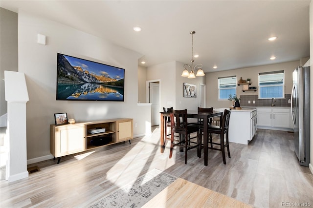 dining room with an inviting chandelier, recessed lighting, light wood-style floors, and baseboards