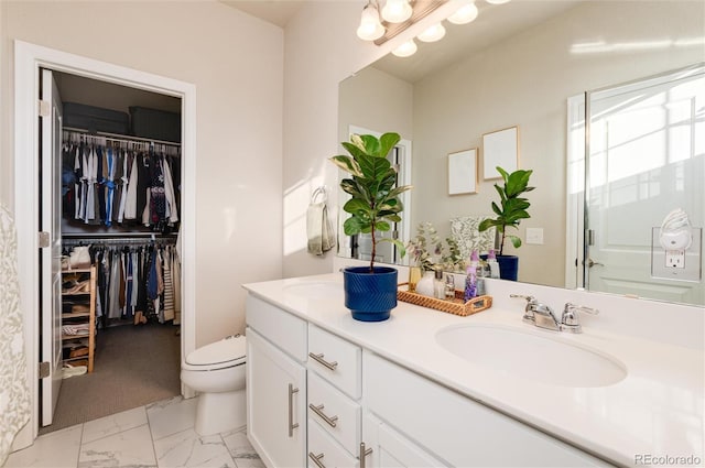 bathroom with a spacious closet, toilet, double vanity, marble finish floor, and a sink