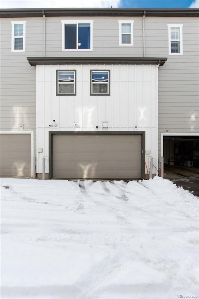 snow covered rear of property featuring board and batten siding